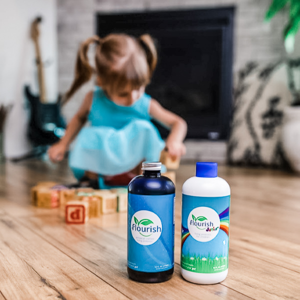 Flourish Probiotic bottles on floor in front of young girl playing